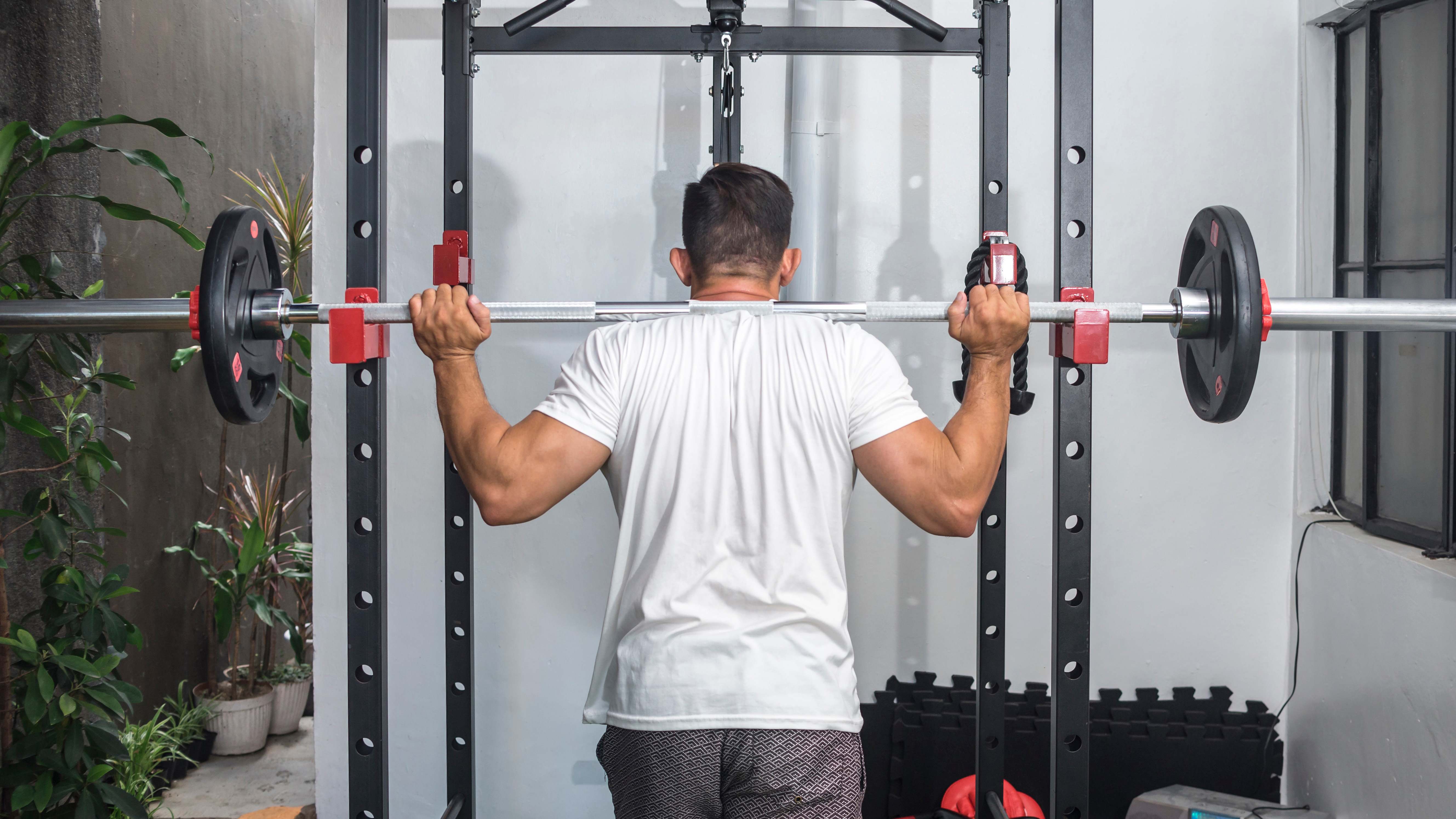 Man setting up on a squat rack placing bar on his back with weights loaded on barbell