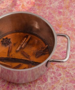 Cinnamon sticks in oil in pan on a mottled abstract pink countertop