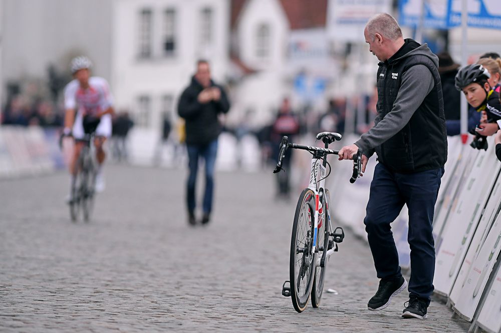 A mechanic walks Mathieu van der Poel's bike to theline after the cyclo-cross world champion crashed at Nokere Koerse