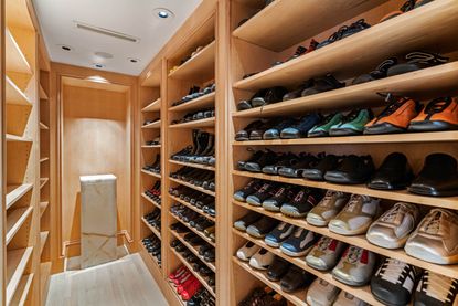 A large walk in closet with rows of shoes