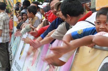 Fans bang the barriers as the race leader nears the finish.
