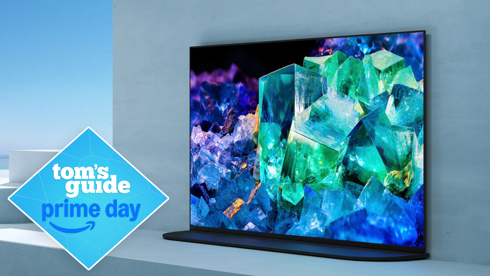 The Sony A95K displaying colorful minerals in an minimalistic, brightly lit room. On the left side of the image is a diamond-shaped badge that reads: "Tom's Guide Prime Day."