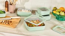 Light green Caraway food storage set on a kitchen counter, showing prepped vegetables, rice, and proteins being stored