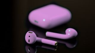 Airpods tinted purple on black background