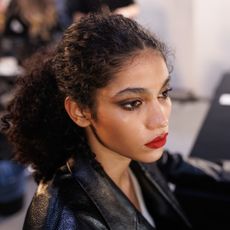 a model backstage at Dsquared2 fall 2025 show wearing red lipstick and eyeliner