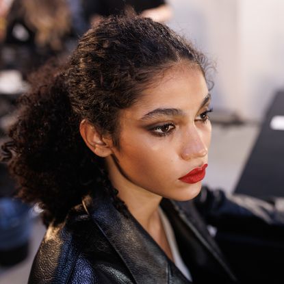 a model backstage at Dsquared2 fall 2025 show wearing red lipstick and eyeliner