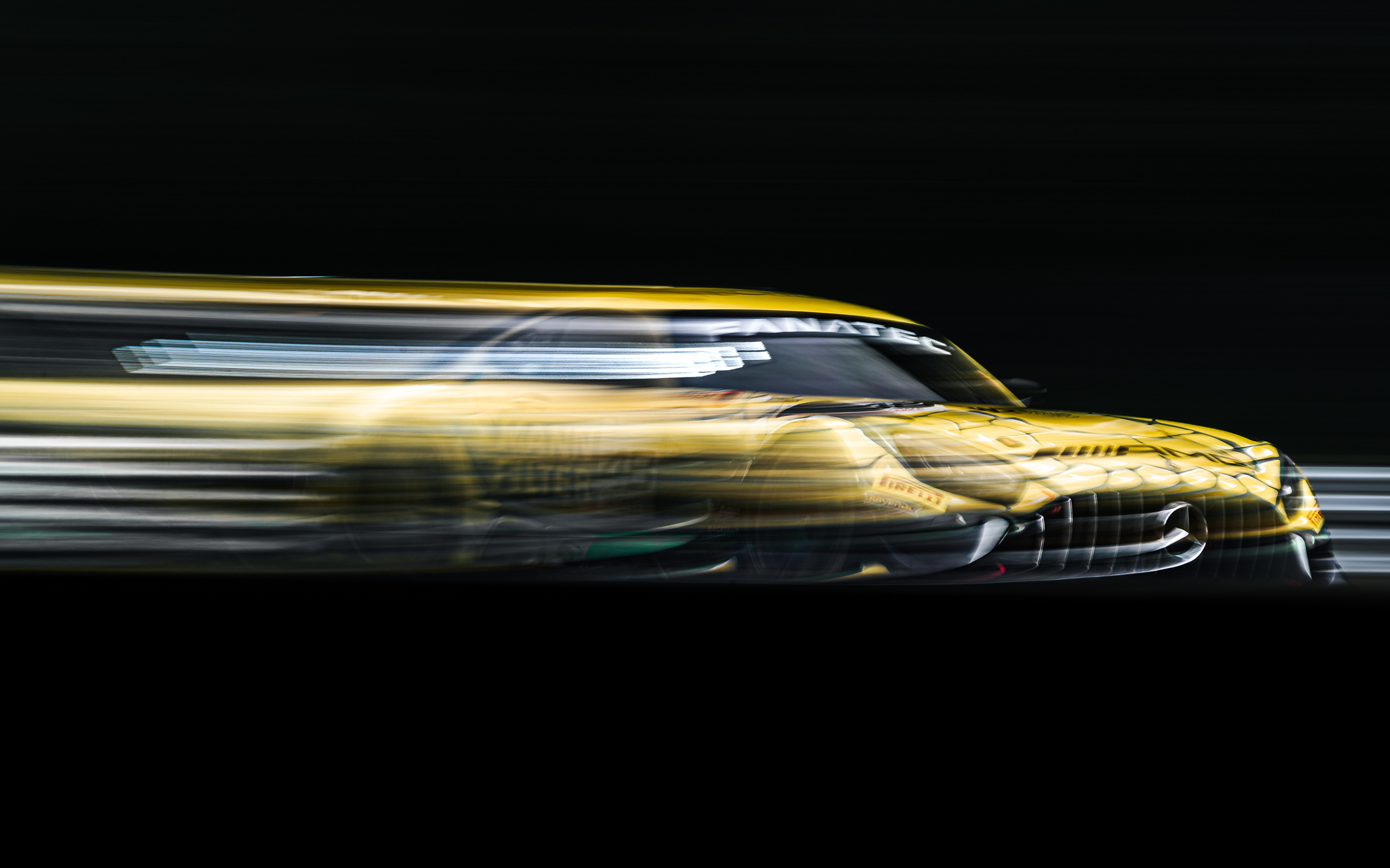 A blurred yellow race car speeding against a dark background, showcasing motion and excitement in motorsport