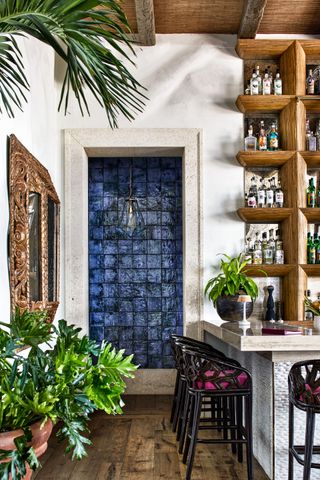 Wooden bar shelf, black bar chairs and blue tiled doorway