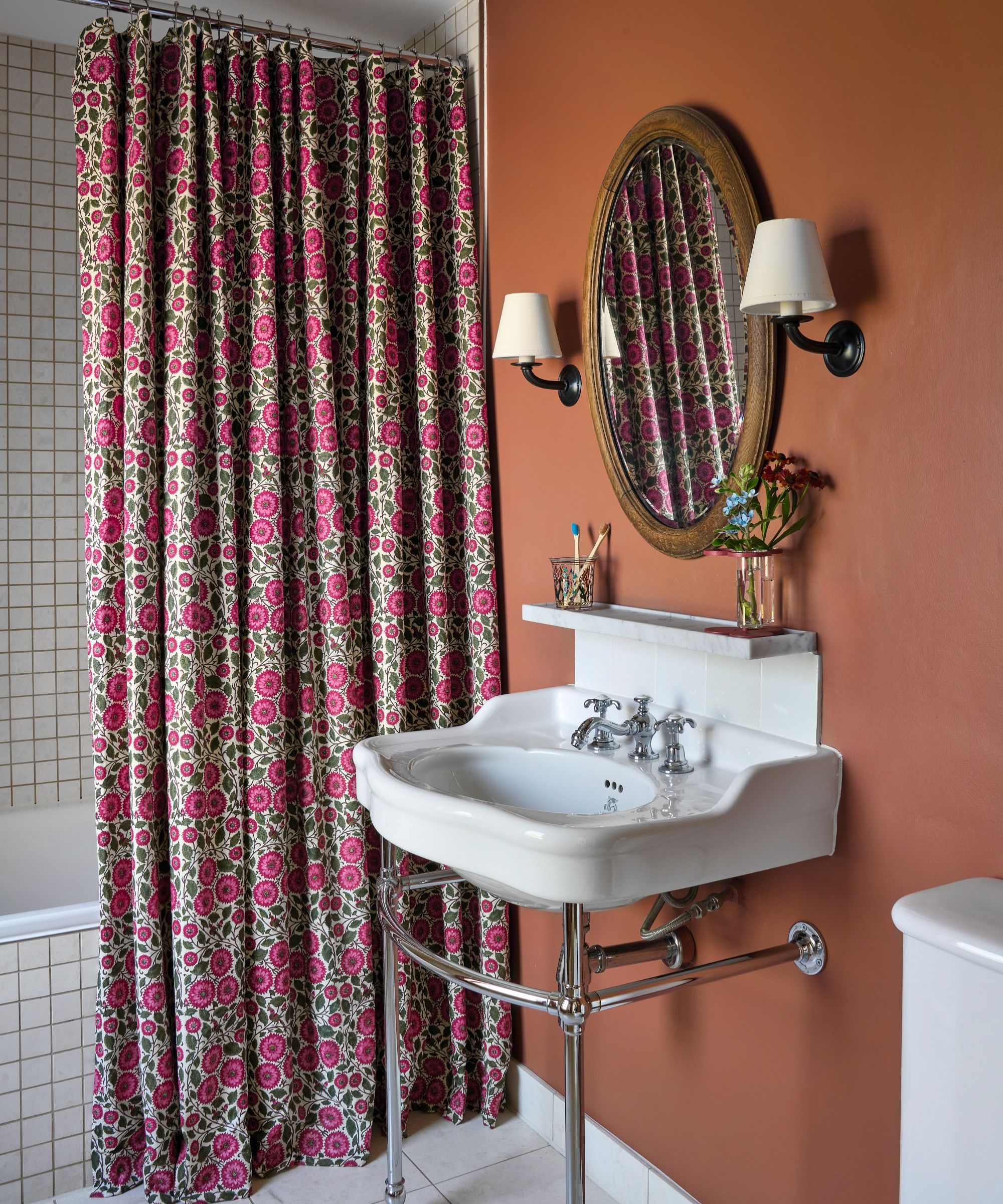 An orange bathroom with a washstand sink and a floral shower curtain