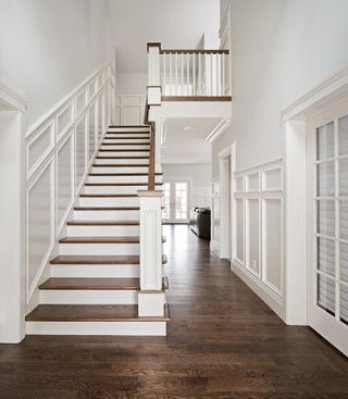 White hallway wall panelling with wooden floors