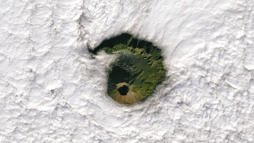 A satellite photo of thick clouds with a gap showing Mount Vesuvius below