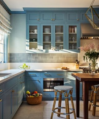 Blue shaker-style kitchen with glazed wall cabinets and a metro tile splashback