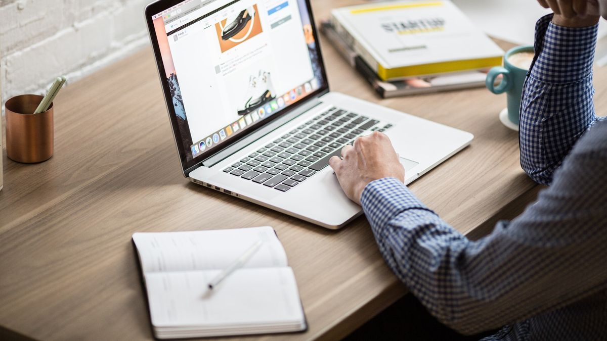 man looking at website on laptop with notepad to the side