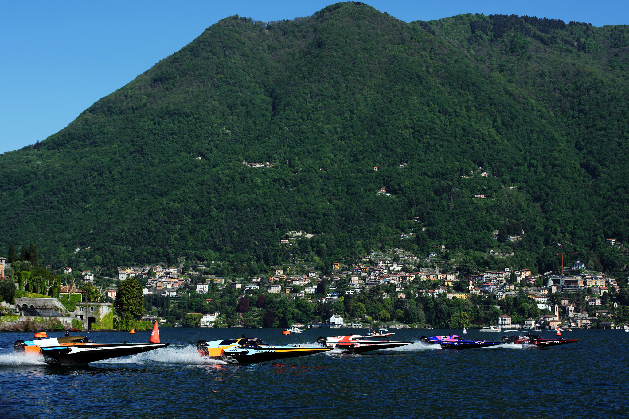 A powerboat speeding along the waters of Lake Como, with italian villas in the background.