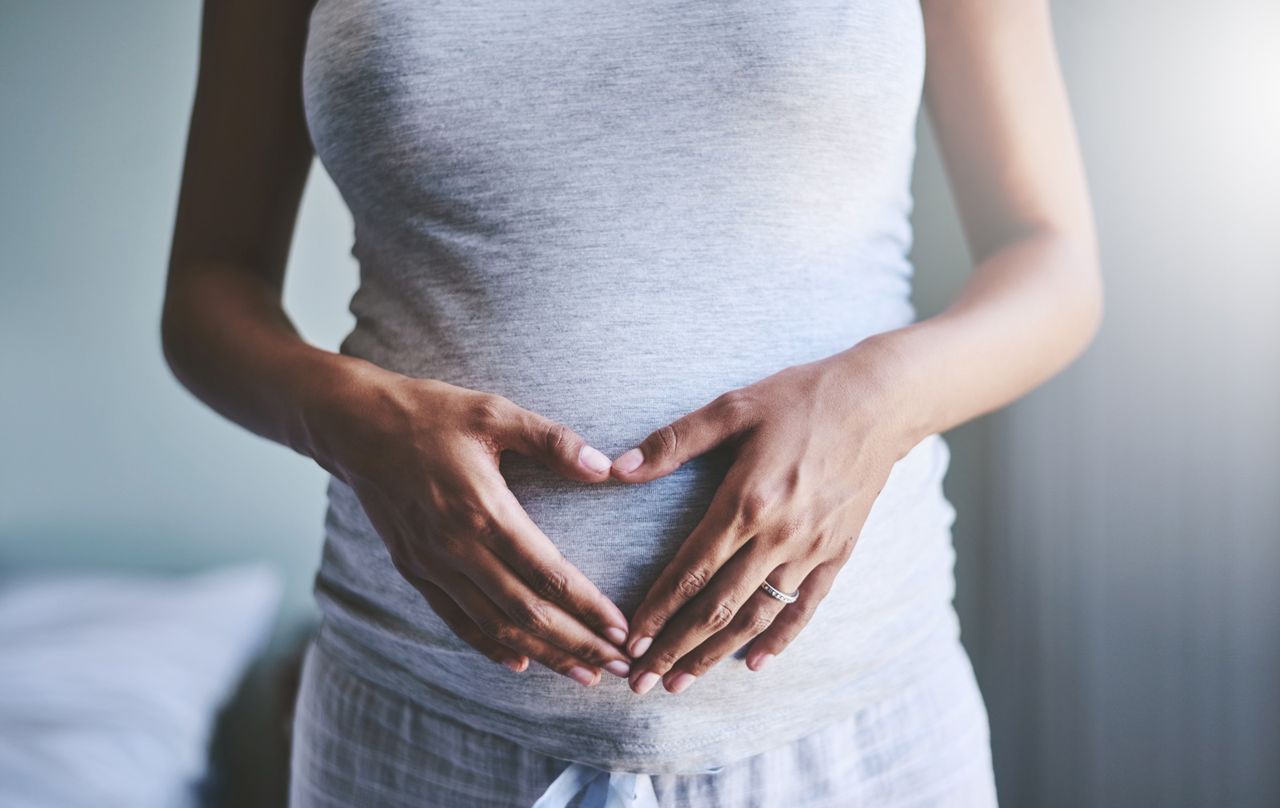 Woman holding her baby bump during pregnancy.