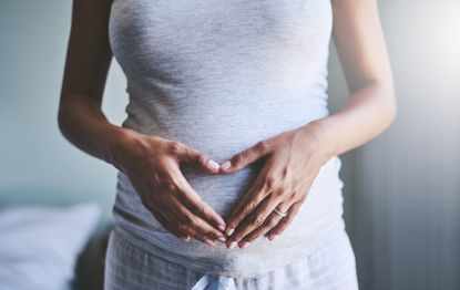 Woman holding her baby bump during pregnancy.