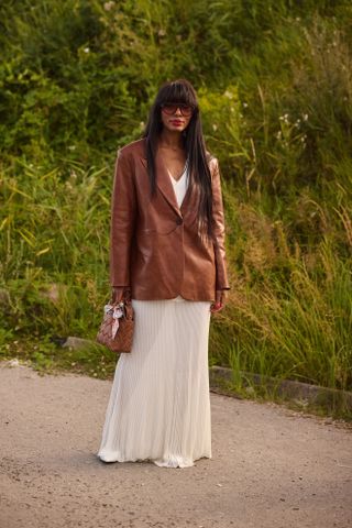 Influencer wears a leather jacket and white skirt.