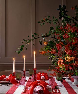 Dining room with red and white festive tablescape, candles, foliage, tableware