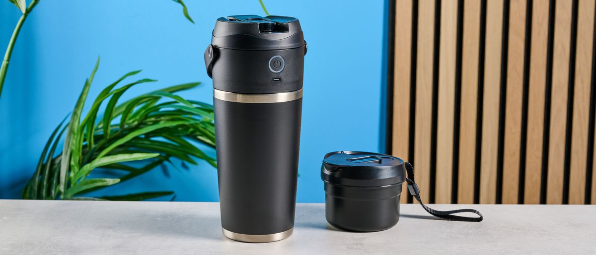 the Nutribullet Flip with a black insulated tumbler and a portable battery-powered blade photographed with a blue background. The tumbler has a carry strap and a sippy lid you can interchange, and an on/off button on the base. 