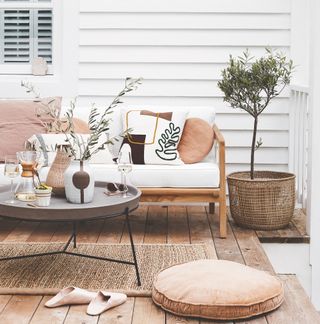 garden decking against white clapboard wall with boho furniture and accessories