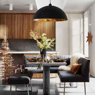 Contemporary kitchen diner with L-shaped bench topped with oversized pendant