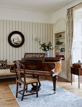 grand piano in living room with striped wallpaper and alcove shelves and Georgian sash windows