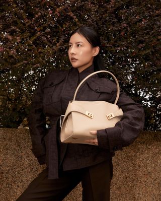 Woman wears brown handbag carries beige bag