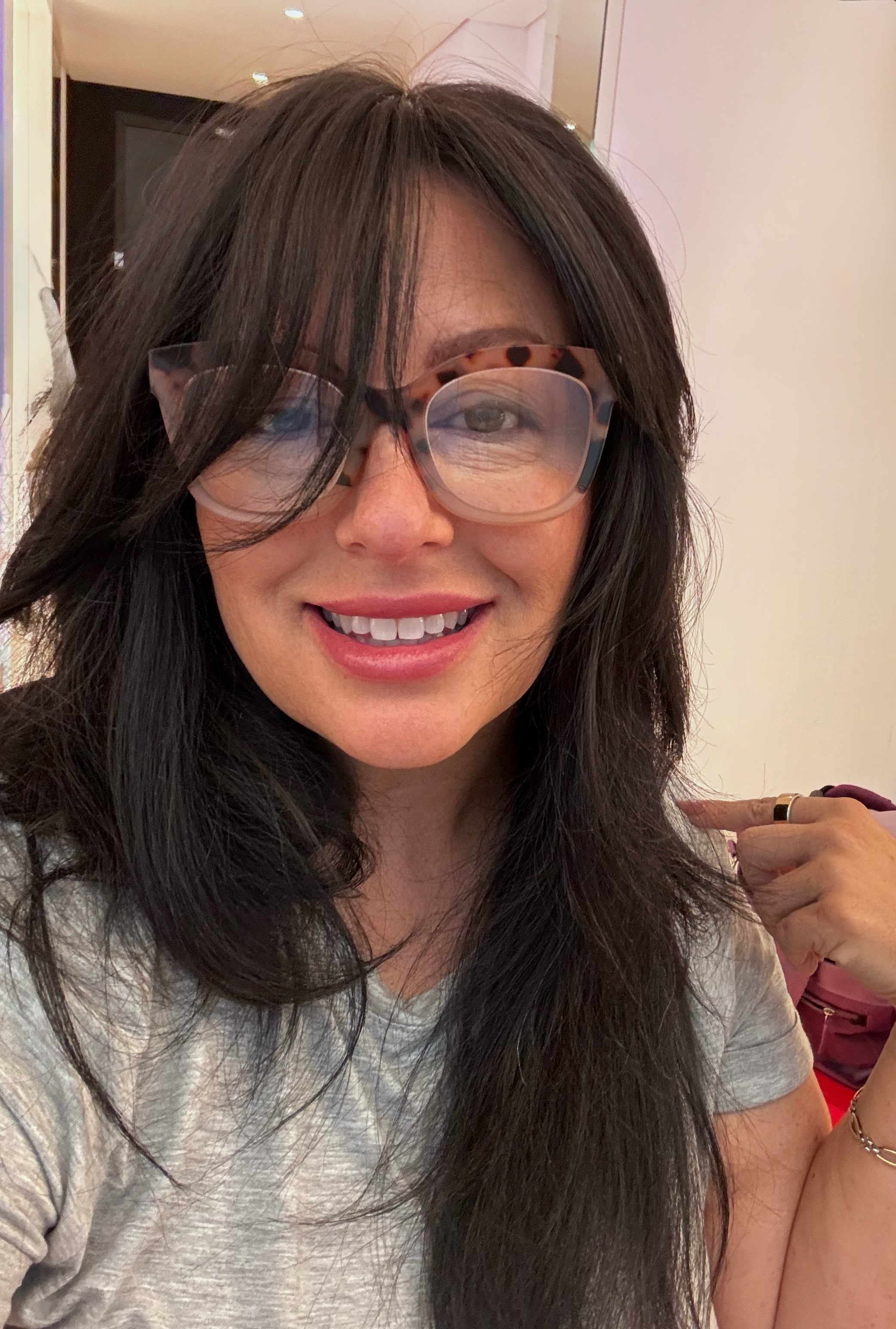 a white woman with dark hair and glasses in a gray t shirt