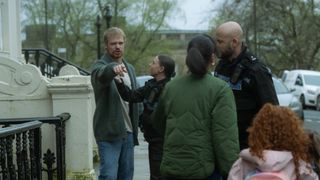 Jan pointing at Rebecca outside their home in front of police