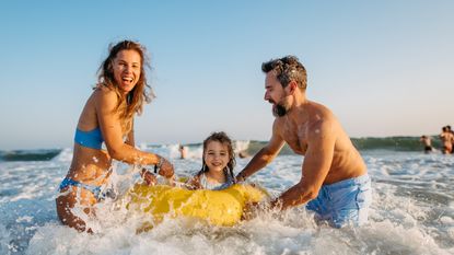 Parents play with their child in the sea