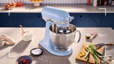 Image of the new kitchenaid colour of the year 2024 in light iridescent blue on top of a kitchen counter surrounded by food