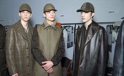Three models stood next to each other with coats and hats on