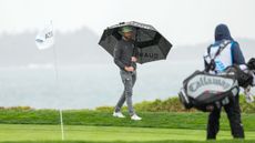 Chris Kirk holds an umbrella at Pebble Beach