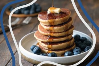 A stack of American pancakes topped with blueberries and a square of butter