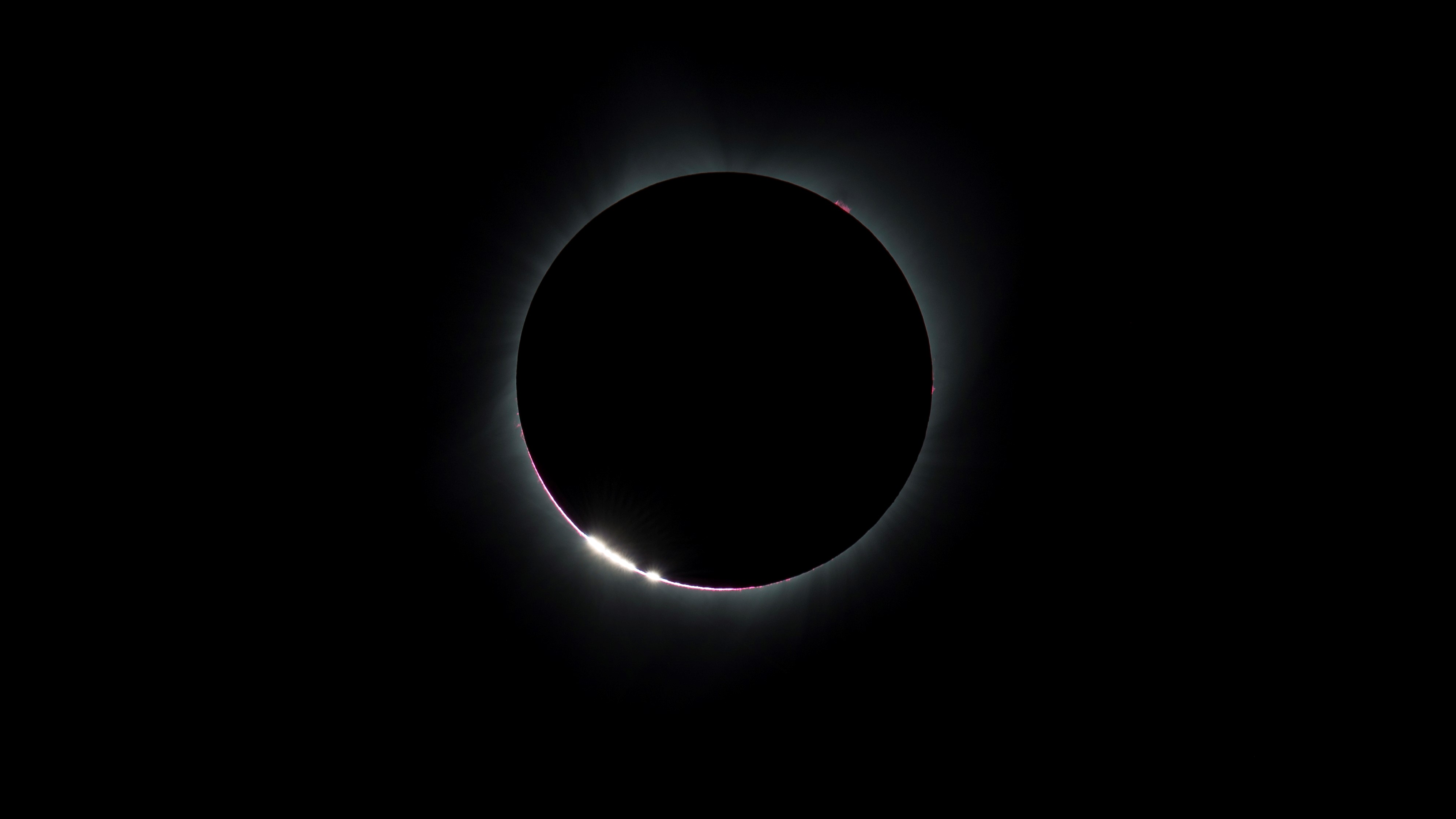 Grãos brilhantes de luz são produzidos em torno da borda de um eclipse solar pré-total.