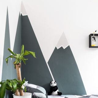 A children's room with a painted mountain mural by the bed