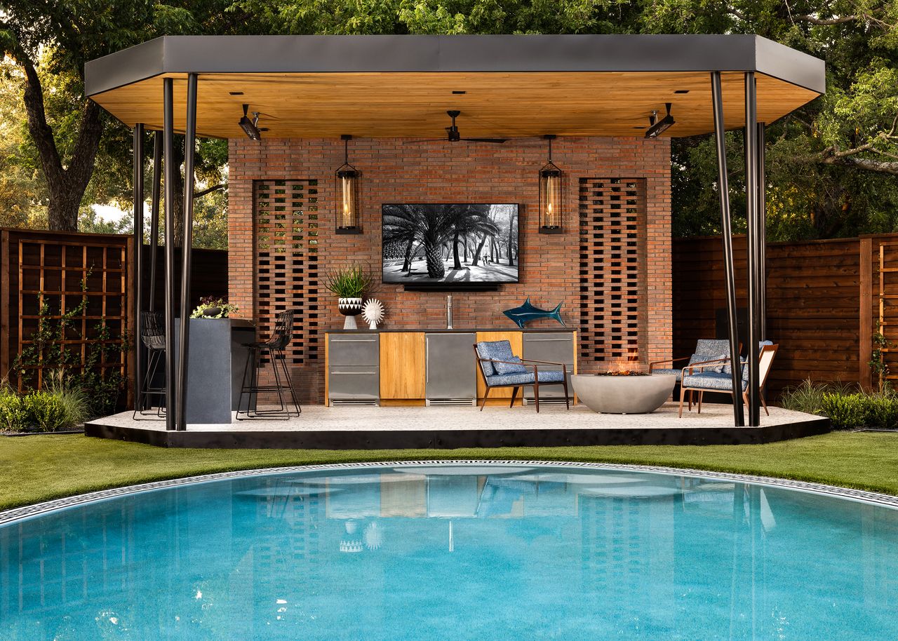 An outdoor kitchen and seating area under a canopy