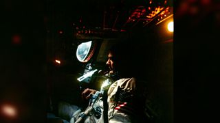 Buzz Aldrin sits in a dimly lit spacecraft.