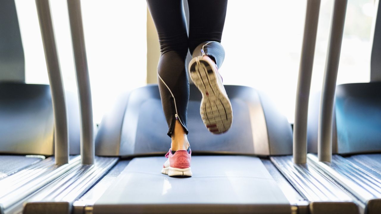 Woman wearing sneakers and tights running on treadmill