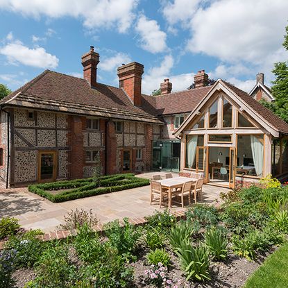 house exterior with bricked wall and lawn with tables and chairs