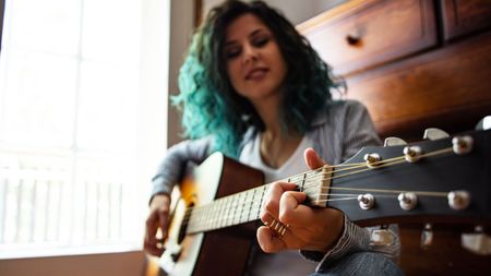 Woman playing a guitar chord on an acoustic guitar