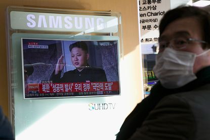 A South Korean goes about his business as North Korean leader Kim Jong Un talks on TV