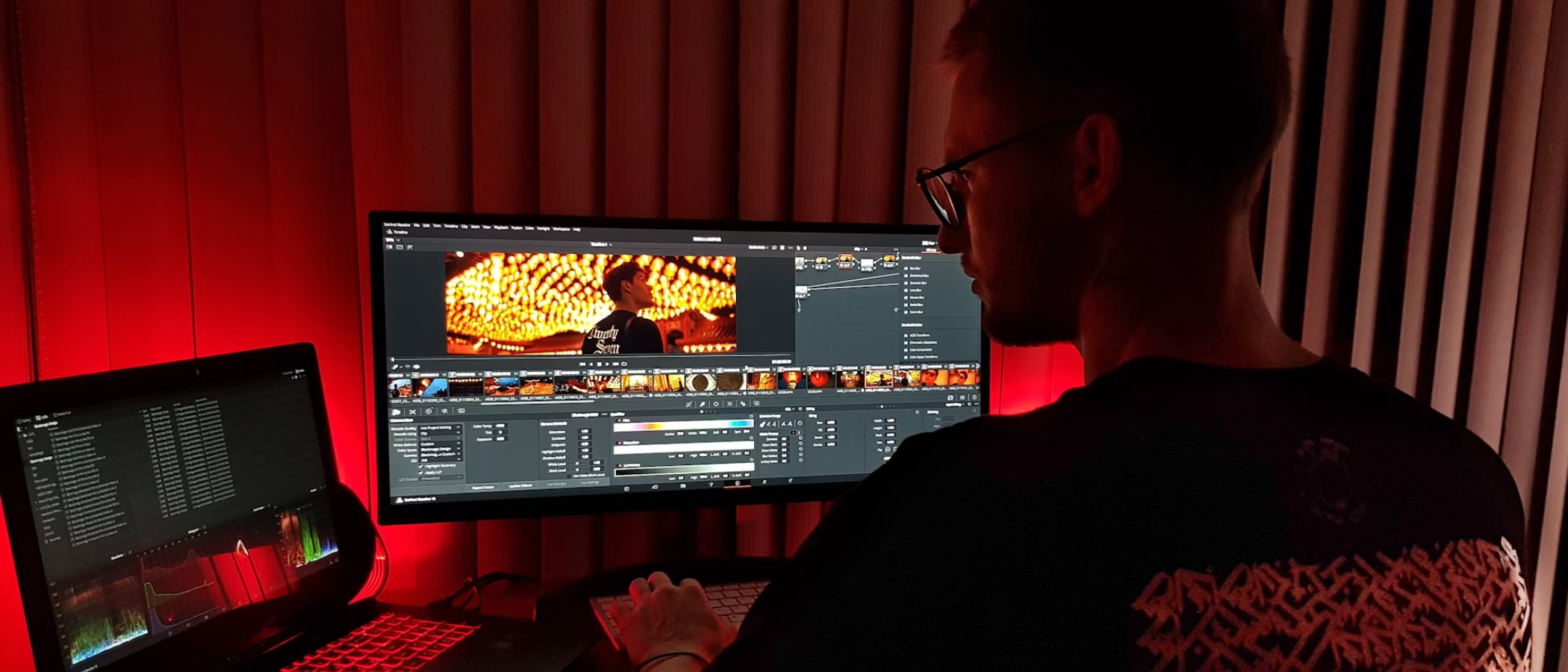 Man using a laptop to edit videos in a darkened home office