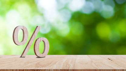 Close-up of percent sign leaning on a wooden table