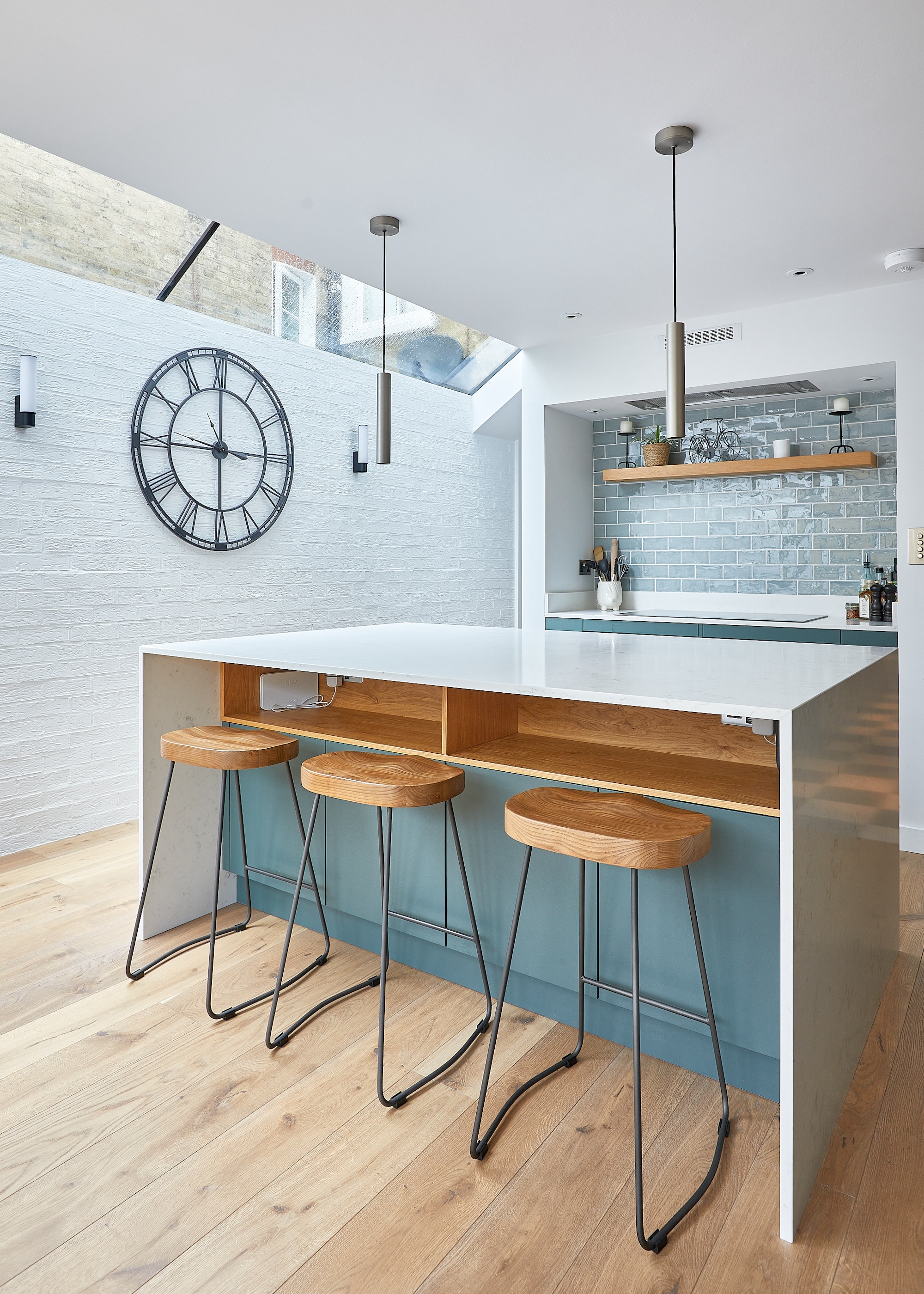 a kitchen island in a modern home with bar stools beside it. there are also hanging pendant lights above the island.
