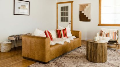 Neutral small living room with brown leather sofa and wooden floors