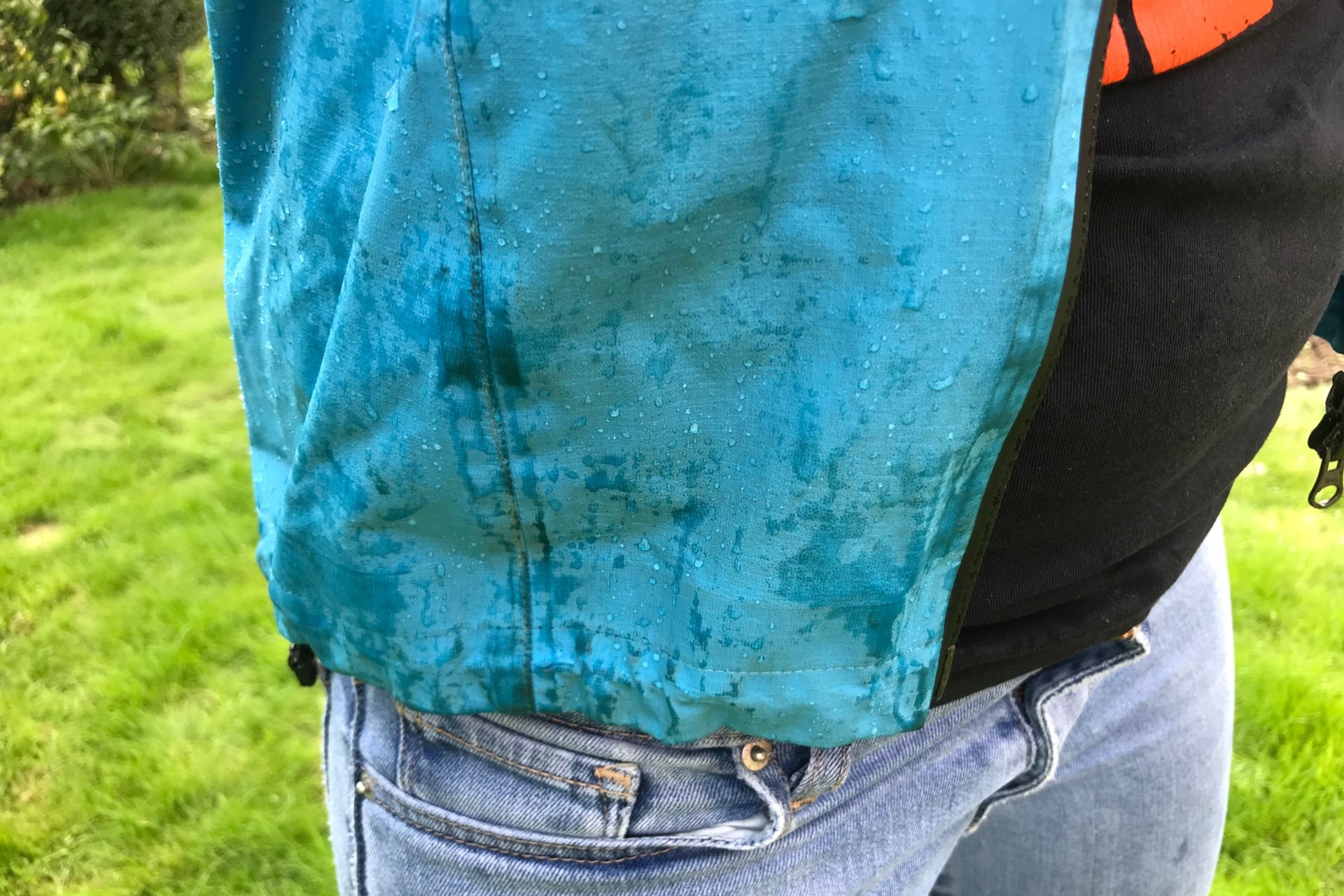 The bottom of this blue/green jacket in this image shows water soaking the fabric