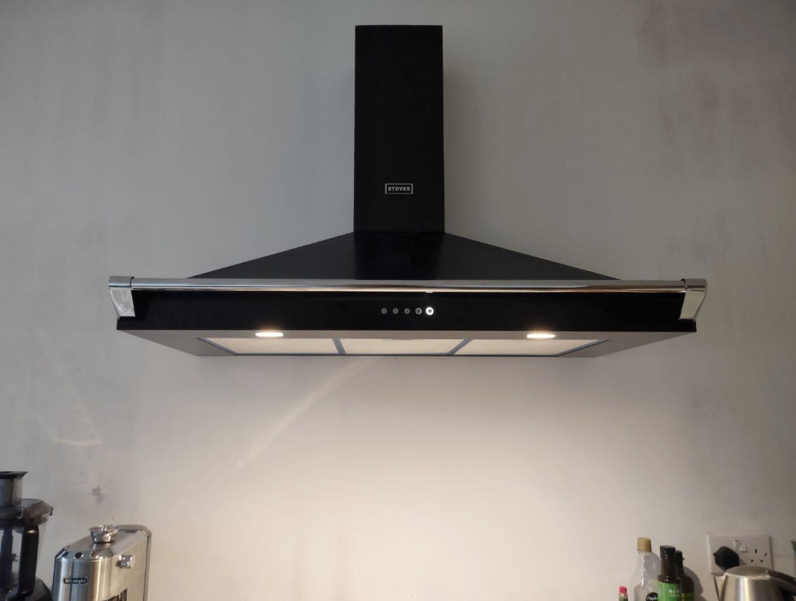 A black cooker hood with led lights on a white kitchen wall