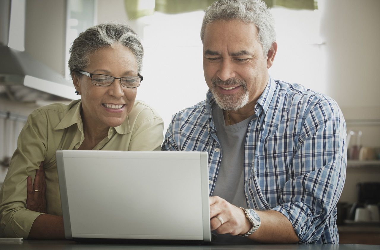 Hispanic couple using laptop in kitchen