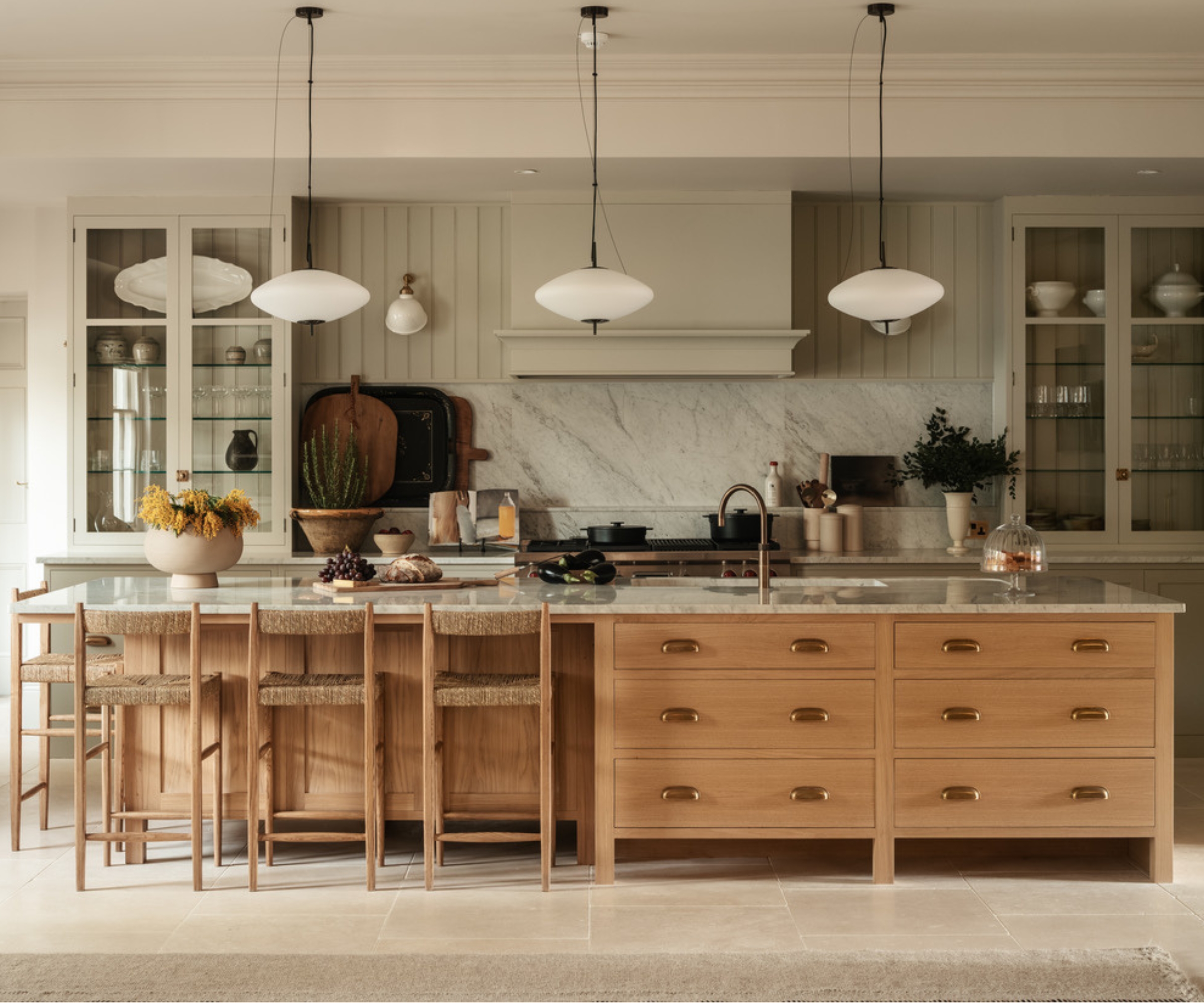A green kitchen with a large wooden island featuring storage on one end and seating on the other